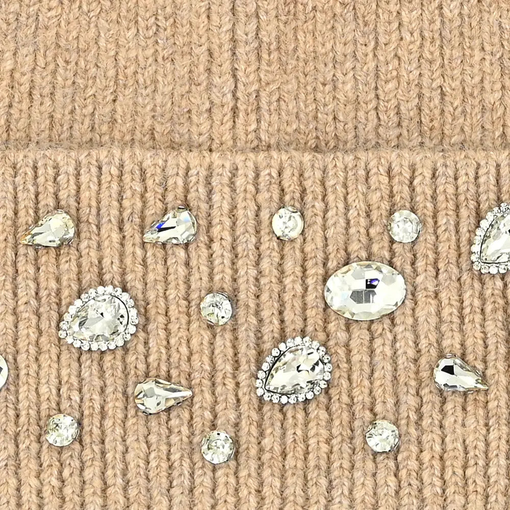 Close-up of a beige ribbed knit fabric embellished with scattered clear rhinestones and crystal-like studs.
