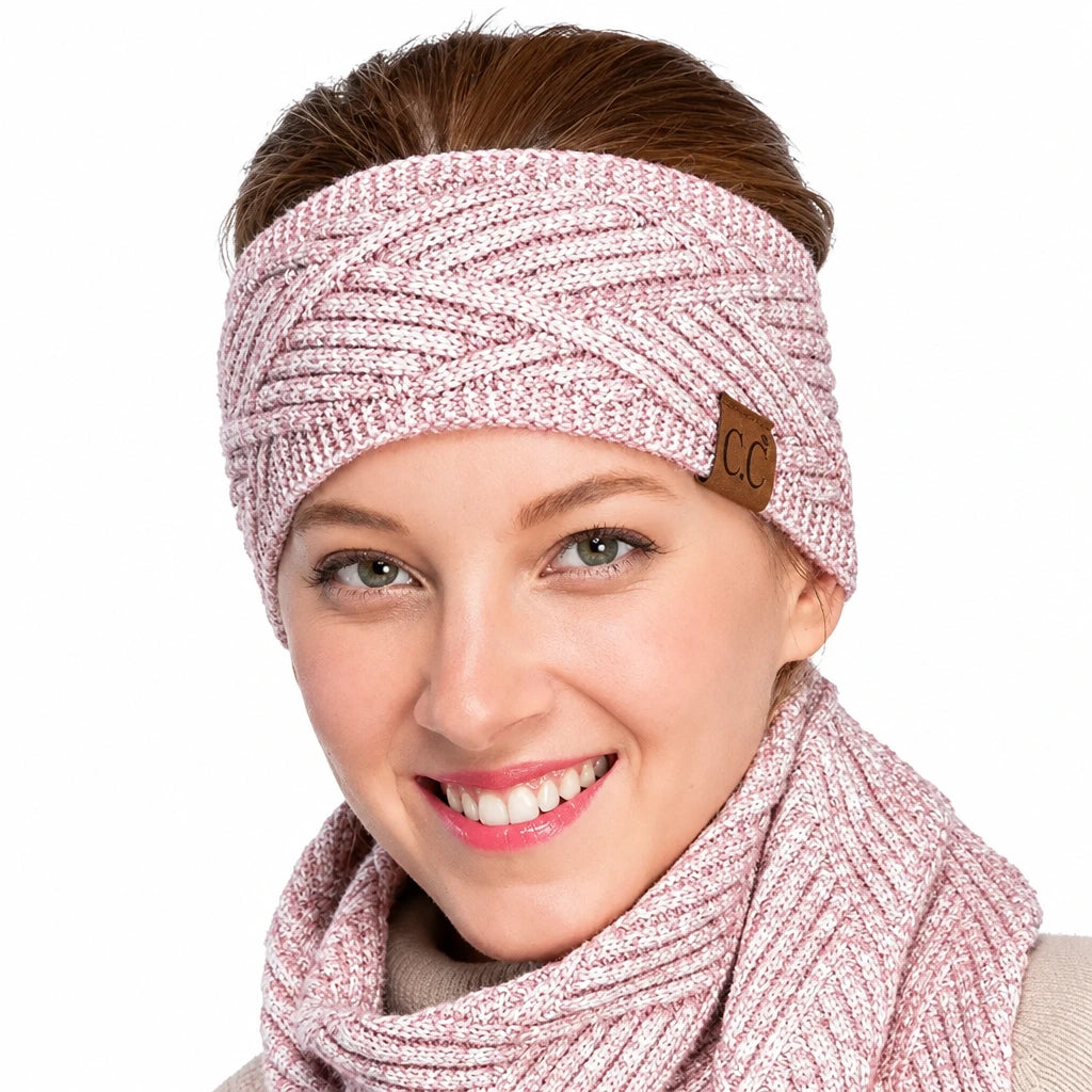 A smiling woman wearing a light pink marled knit headband with a small brown leather patch featuring the letters 'CC', paired with a matching pink knit scarf against a plain white background.